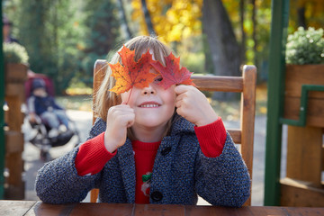 Girl playing with autumn leaves.