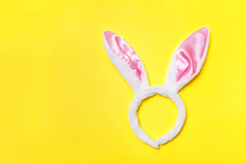 Happy Easter concept. Preparation for holiday. Decorative bunny ears furry fluffy costume toy isolated on trendy yellow background. Simple minimalism flat lay top view copy space