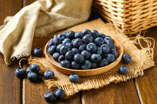 Fresh blueberries in wooden plate on a wooden table