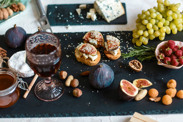 Sandwiches with ricotta, fresh figs, walnuts and honey on rustic wooden board over black backdrop, top view. concept of Italian cuisine