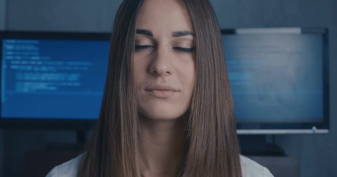 Young Woman Developer Programmer looking at camera at binary code background