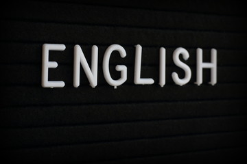 The word English in white plastic letters on a black notice board 