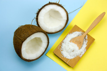 flat lay coconut and cocnut flakes  on a yellow and blue background