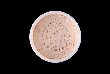 Natural mineral powder in a jar, top view, isolated on black background