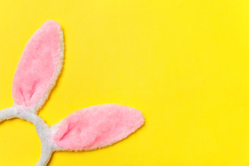 Obraz na płótnie Canvas Happy Easter concept. Preparation for holiday. Decorative bunny ears furry fluffy costume toy isolated on trendy yellow background. Simple minimalism flat lay top view copy space