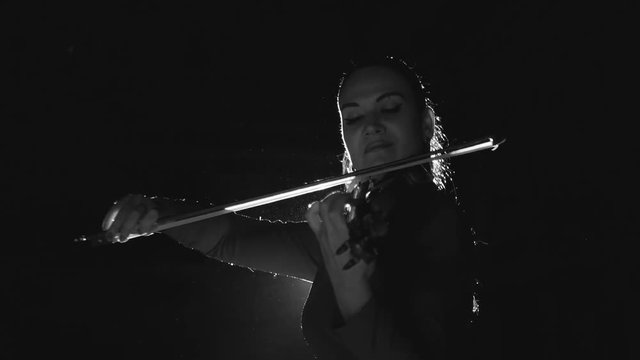 beautiful young girl playing the violin during the concert.black and white
