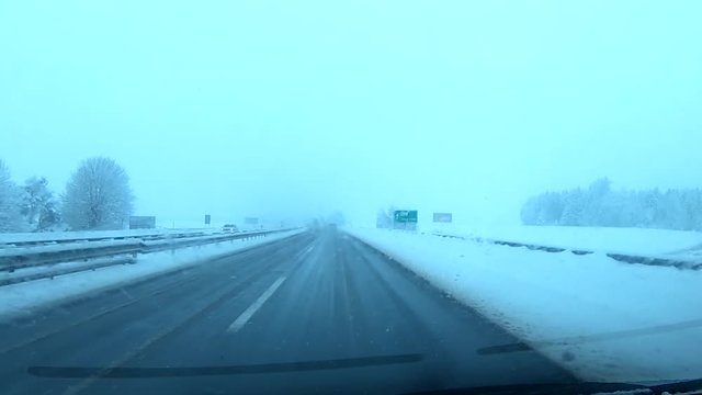 Driving on not quite safe snowy highway in Citroen Picasso car on a snowing day.