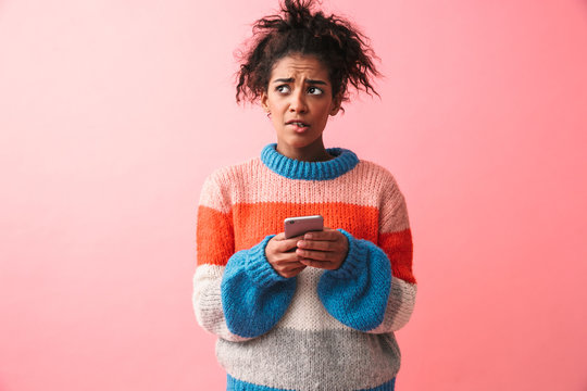 Sad Beautiful Young African Woman Posing Isolated Over Pink Wall Background Using Mobile Phone.