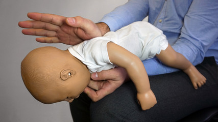 Back blows (the Heimlich maneuver or Heimlich manoeuvre) on a simulation mannequin infant dummy during medical training Basic Life Support