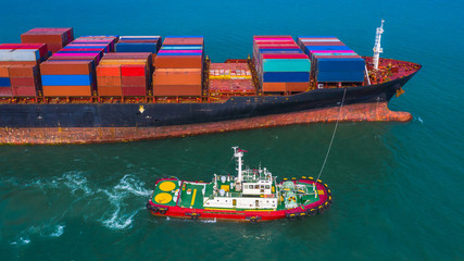 Cargo freight ship carrying container and small pilot boat.
