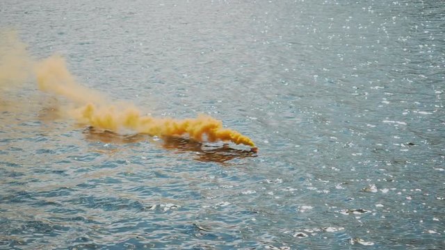Slow motion of a water smoke bomb distress beacon releasing a stream of smoke during a training exercise in boat emergency survival