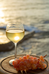Aperitif cold white wine served in glasses with pink grapes on outdoor tessace witn sea view