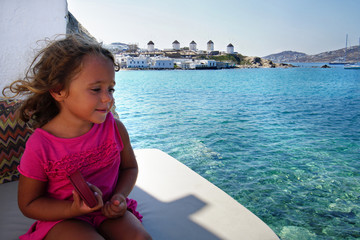 Happy little girl on vacation in Mykonos admires the view, Cyclades
