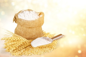 Sack of flour with wheat and scoop isolated on white background