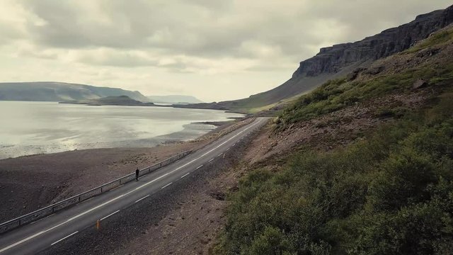 Drone approaching a man skating through the beautiful Icelandic landscape.