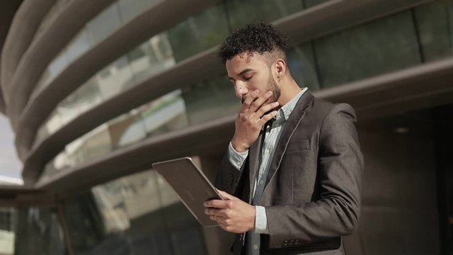 Serious confident man wearing formal wear holding tablet.