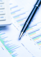 pen,glasses and calculator on Financial accounting stock market graphs analysis chart