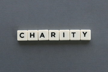 Charity word made of square letter word on grey background.