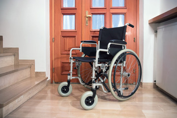 Fototapeta na wymiar empty wheelchair at home, object symbol of disability near the stairs