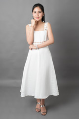 Naklejka premium Beautiful woman in white dress portrait in studio, grey background