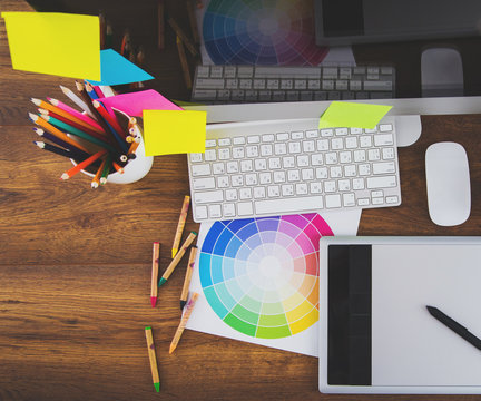 Modern office workplace with digital tablet, notepad, colorful pencils, glasses, in morning