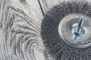 Wire brush for of electric drill on wooden background, macro, closeup