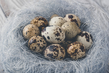 Easter decoration. Quail eggs in a nest on a wooden background