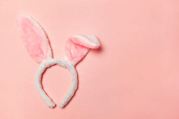 Happy Easter concept. Preparation for holiday. Decorative bunny ears furry fluffy costume toy isolated on trendy pastel pink background. Simple minimalism flat lay top view copy space