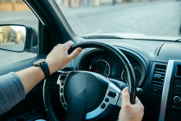 view from inside man driving car. hands on steering wheel.