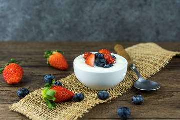 Bowl of homemade granola with Greek yogurt and fresh berries mix on wooden background from top view. Healthy blueberry and Strawberry parfait in a jar.