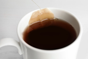 Teabag in cup with hot fresh drink, closeup