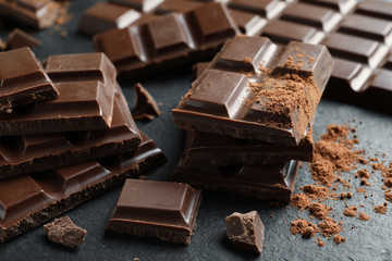 Pieces of tasty chocolate on slate plate, closeup