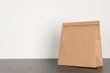 Paper bag on table against white wall. Mockup for design