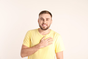 Young man holding hand on his heart against white background