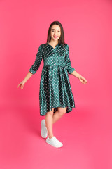 Portrait of beautiful young woman in stylish dress on color background