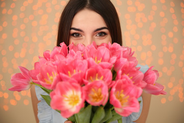 Beautiful girl with spring tulips on blurred background, closeup. International Women's Day