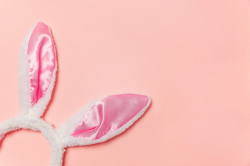 Happy Easter concept. Preparation for holiday. Decorative bunny ears furry fluffy costume toy isolated on trendy pastel pink background. Simple minimalism flat lay top view copy space