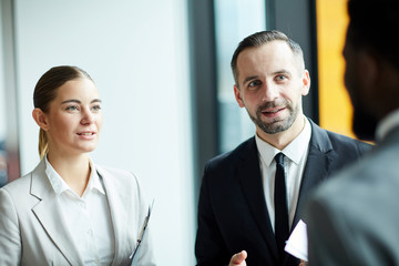 Elegant businessman and businesswoman discussing some working points with their foreign colleague