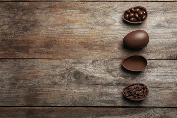 Flat lay composition with chocolate Easter eggs on wooden background, space for text
