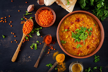 Indian dal. Food. Traditional Indian soup lentils.  Indian Dhal spicy curry in bowl, spices, herbs, rustic black wooden background. Top view. Authentic Indian dish. Overhead. Flat lay