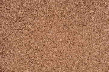 Rough background from texture plaster on a brown wall.