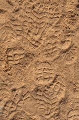 footprints from the surface of shoes on coarse yellow sand.