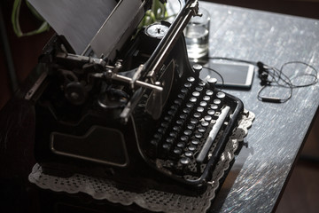 Workplace of an old school writer with mobile phone headphones and a typewriter