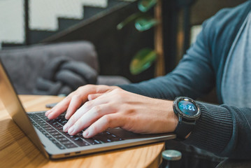 man hand close up working on laptop smart watch on wrist
