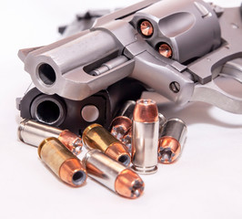 Obraz premium Two handguns, a 40 caliber pistol and a 357 magnum revolver with 40 caliber bullets on a white background