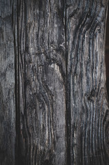 Vertical background of old weathered dark brown cracked wooden gnarled boards close-up