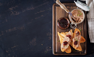 Chicken homemade liver paste or pate in glass jar with toasts and lingonberry jam with chili. Top view, copy space