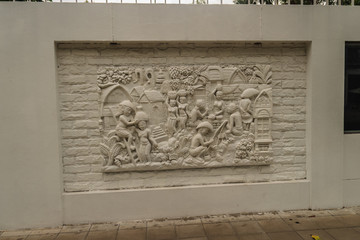 Beautiful white Java stucco patterned on the boundary wall. Vintage white wall bas-relief stucco in plaster, depicts Lotus flowers background.