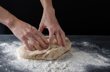 Woman kneading dough on sprinkled with flour table. Yeast dough for bread, rolls, pizza, focaccia...