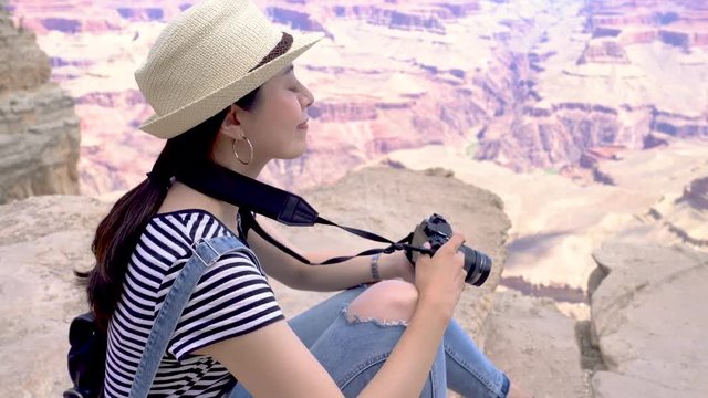 attractive young girl using professional camera taking photo of desert view while sightseeing in Grand Canyon National Park. female lens man hiker smiling to friend in back and photographing.